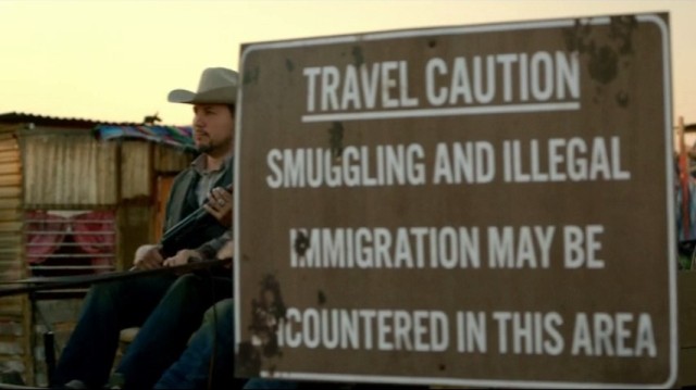 Revolution S2x10 - Miles, Rachel and Bass pass by an illegal immigration sign warning as they volunteer to pick tomatos